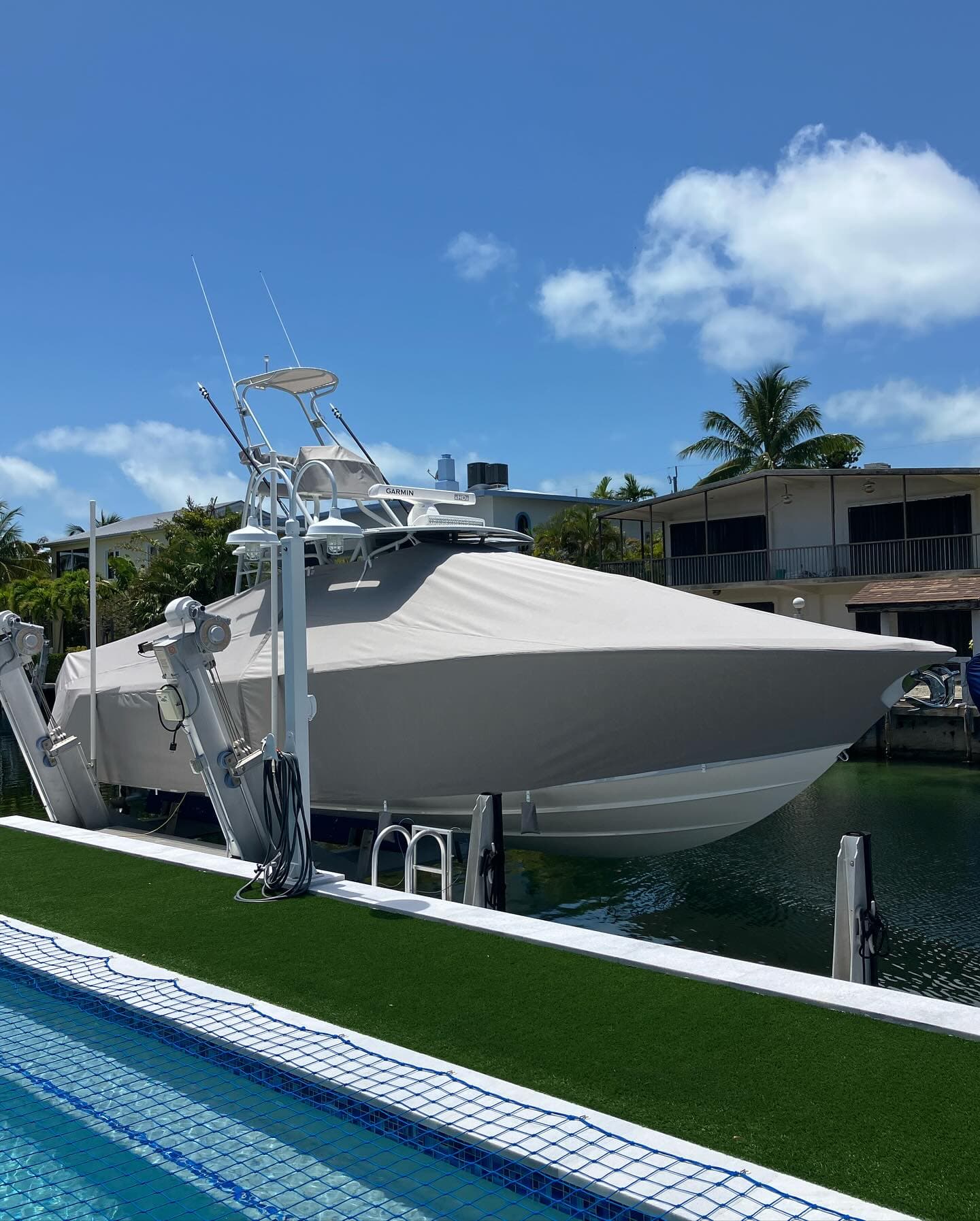 Grey custom-fit cover over a center console boat raised on a canal lift
